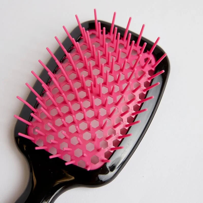 Silqé pink and black paddle hairbrush for wet hair detangling, featuring flexible bristles and a honeycomb vented base.