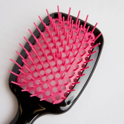Silqé pink and black paddle hairbrush for wet hair detangling, featuring flexible bristles and a honeycomb vented base.