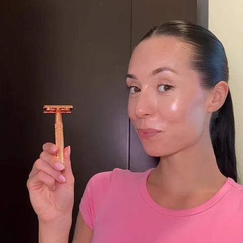 A woman holding the SmoothShave rose gold safety razor, showcasing its premium brass handle for a smooth facial shave.