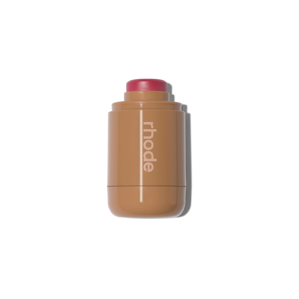 Teacup shade dewy cream blush stick by Rhode in a compact tan pocket-sized applicator on a black background.