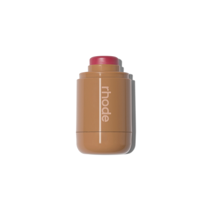 Teacup shade dewy cream blush stick by Rhode in a compact tan pocket-sized applicator on a black background.